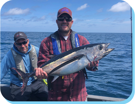 Two men holding a fish on the ocean.