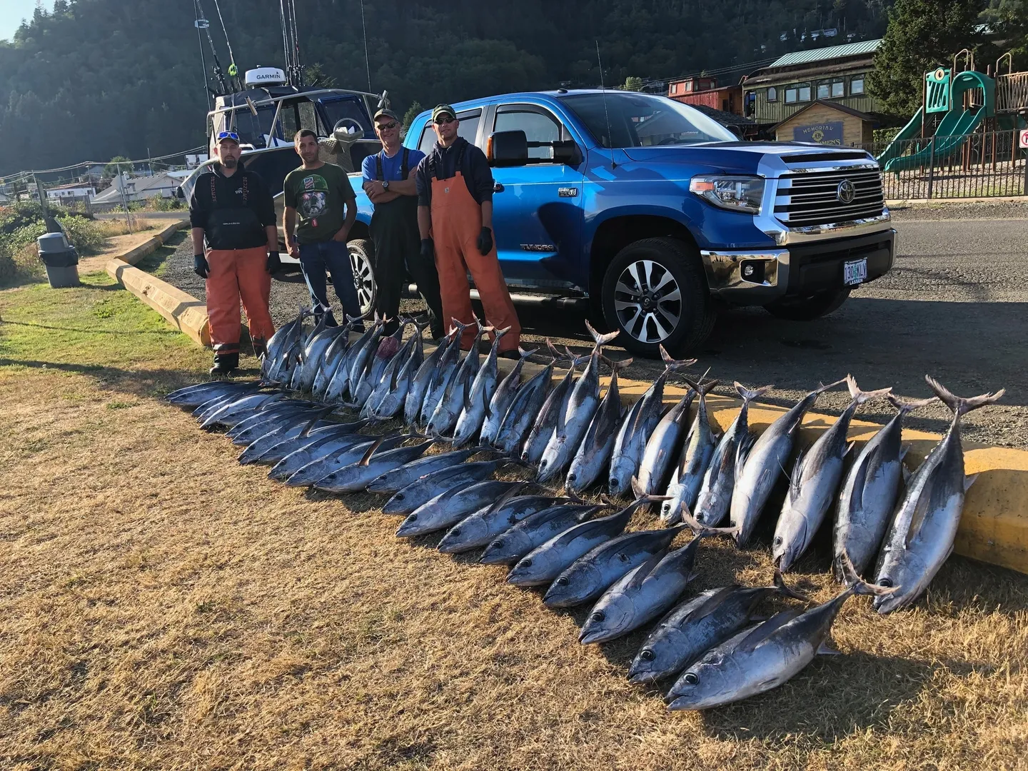 A group of people standing next to a truck with fish.