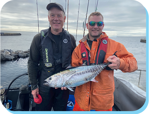 Two men holding a fish on the side of a boat.