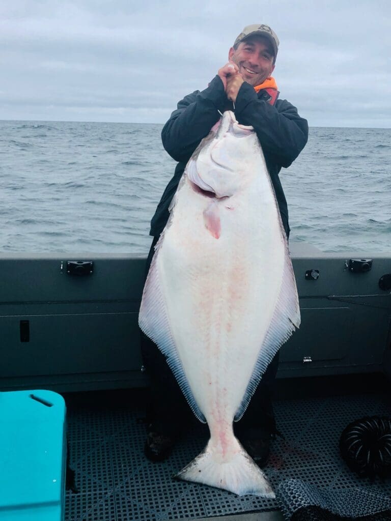 A person sitting on the back of a boat holding onto a fish.